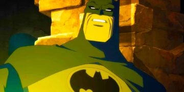 Animated Batman in a torn cape standing in front of a stone wall in Batman: The Dark Knight Returns
