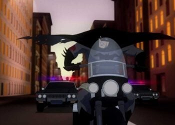 Animated Batman speeding on a motorcycle with police cars in pursuit through Gotham City in Batman: Year One