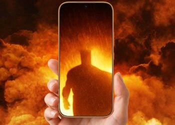 Honor 600 smartphone held up displaying a cinematic silhouette in dramatic firelight
