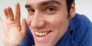 Jim Carrey as Chip Douglas grinning and waving at close range in The Cable Guy (1996)