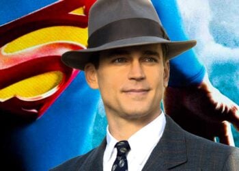 Matt Bomer in a suit and fedora in front of the Superman logo