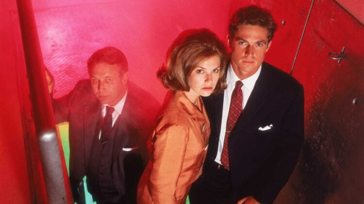 Three Dark Skies cast members in a tense stairwell scene lit in red and green