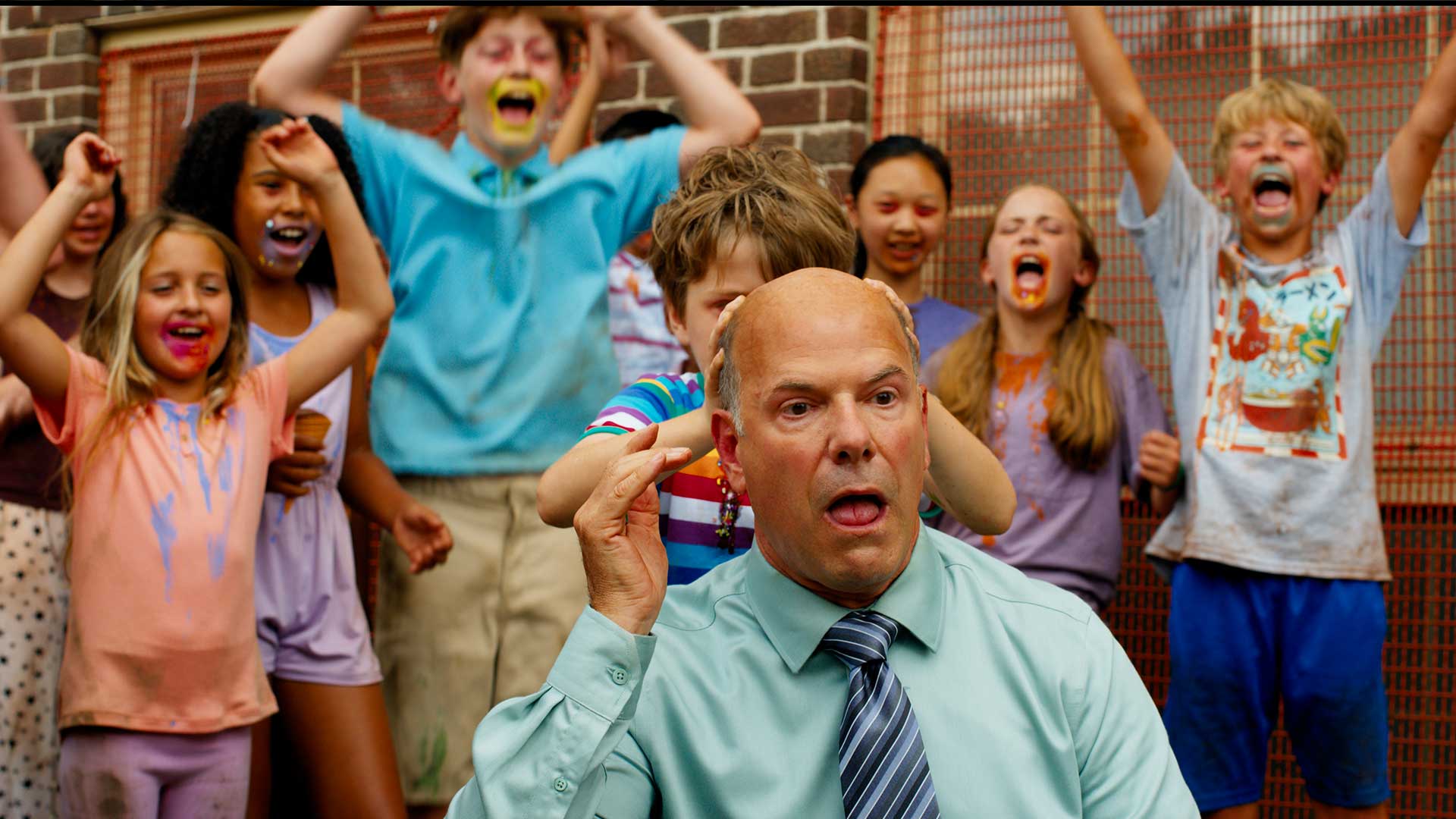 A bald man reacts in shock as children cheer behind him in Ice Cream Man