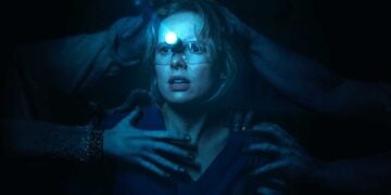 Amelia Eve as Gemma wearing a headlamp, reaching hands grabbing at her in the dark in Insidious: Out of the Further